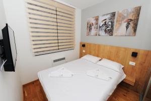 a small bedroom with a bed and a window at Perla apartman Titova vila in Palisat