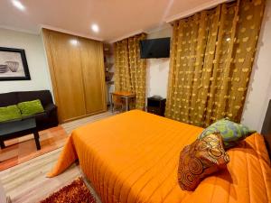 a bedroom with an orange bed and a couch at Ronda De Don Bosco52 By Vigovacaciones in Vigo