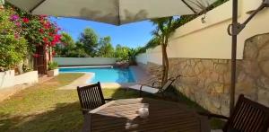 un patio trasero con piscina y una mesa con sombrilla en VILLA Bed and Breakfast - kitchen, Pool, Barbecue and Large garden en Benidorm