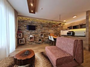 a living room with a couch and a brick wall at Lux Apartman Lucky in Kopaonik