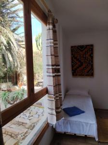1 dormitorio pequeño con ventana y 1 cama en la parte delantera en Taghazout Hill Retreat, en Taghazout