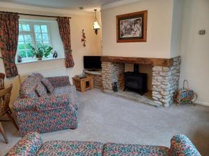 a living room with a couch and a fireplace at Magpie Cottage in South Brewham
