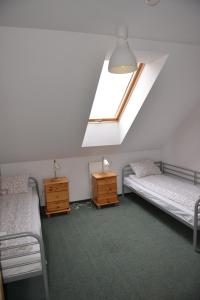 a attic room with two beds and a window at Pokoje Gościnne Domu Pielgrzyma w Supraślu in Supraśl