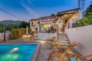 a house with a swimming pool and some chairs at Villa Rhapsody in Hreljin