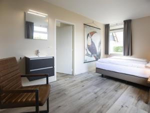 a bedroom with a bed and a chair and a mirror at Holiday Home in Nijmegen near City Centre in Mook
