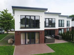 une grande maison blanche avec des fenêtres noires dans l'établissement Ferienhaus in Damp am Ostseestrand, à Damp