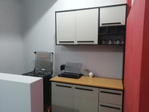 Il comprend une petite cuisine équipée d'une cuisinière et de placards blancs. dans l'établissement Apartamento familiar, à Tarapoto