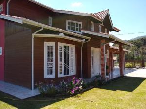 a brown house with flowers in the yard at Rosa dos Ventos - CASA in Urubici