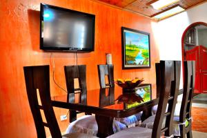 TV en una pared con mesa y sillas en Hotel Itzamana, en Iza