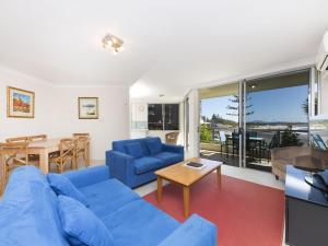 un soggiorno con divano blu e tavolo di Beachpoint G2 a Forster