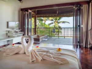 two swans sitting on a bed in a room at Sound of The Sea Villa in Canggu