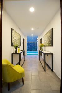 un corridoio con due tavoli e una sedia gialla di Hotel Boutique Casa Loreta a Querétaro