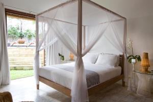 a bedroom with a canopy bed with a window at Sound of The Sea Villa in Canggu