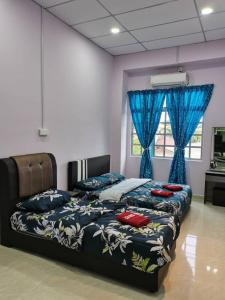 a bedroom with a bed with blue sheets and a window at TAMU HOMESTAY in Kuala Terengganu