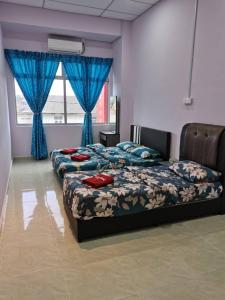 a bedroom with two beds and a window with blue curtains at TAMU HOMESTAY in Kuala Terengganu