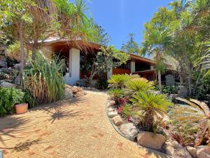 a house with a courtyard with plants and trees at The Boulders - Oceanfront Couple's Retreat with private pool near ferry in Nelly Bay
