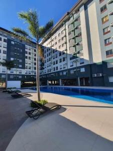 Budget Studio Flat near Airport-Amaia Steps Mandaue Condominium في ماكتان: نخلة أمام مبنى به مسبح