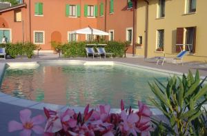 a swimming pool in a courtyard with pink flowers at Corte Castelletto in Nogarole Rocca