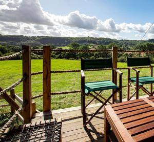 two chairs sitting on a deck with a view of a field at Hakuna Matata Safari Lodge - Sublime, off-grid digital detox with hot tub in Shelsley Walsh