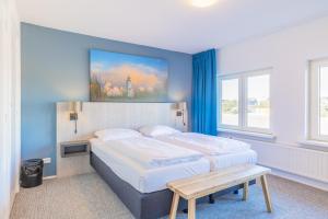 a bedroom with two beds and a blue wall at Hotel De Koningshof in Noordwijk aan Zee