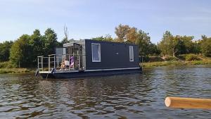 a tiny house on a boat on a body of water at Pływający Dom in Zegrze