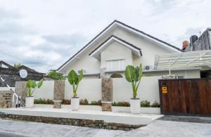 a white house with plants in front of it at Siji Gempol Vacation Home in Yogyakarta