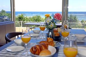 una mesa con comida y vasos de zumo de naranja en オーシャンヴィラ徳之島-Ocean Villa Tokunoshima-, en Tokunoshima