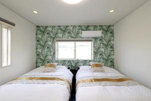 2 Betten in einem kleinen Zimmer mit Fenster in der Unterkunft オーシャンヴィラ徳之島-Ocean Villa Tokunoshima- in Tokunoshima