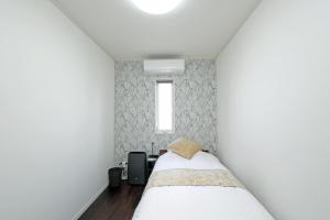 ein kleines Schlafzimmer mit einem Bett und einem Fenster in der Unterkunft オーシャンヴィラ徳之島-Ocean Villa Tokunoshima- in Tokunoshima