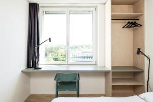 1 dormitorio con ventana y silla junto a la cama en Guesthouse Meiersegg, en Flawil