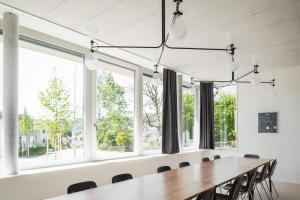 een lange tafel in een kamer met ramen bij Guesthouse Meiersegg in Flawil