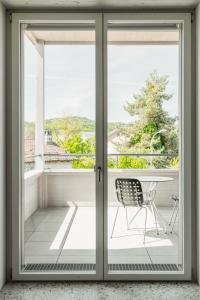 przesuwane szklane drzwi z krzesłem na balkonie w obiekcie Guesthouse Meiersegg w mieście Flawil