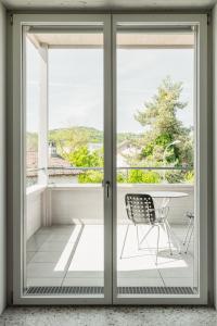 una puerta corredera de cristal con una silla en el balcón en Guesthouse Meiersegg, en Flawil