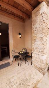 een patio met een tafel en stoelen en een stenen muur bij Flower house in Noto