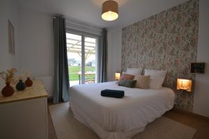 ein Schlafzimmer mit einem großen weißen Bett und einem Fenster in der Unterkunft La Bulle Emeraude, détente à deux, en famille ou entre amis in Plancoët