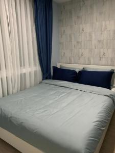 Cama blanca con almohadas azules y ventana en My Resort Hua Hin A206 en Hua Hin