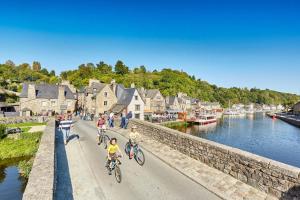 eine Gruppe von Menschen, die auf einer Straße neben einem Fluss Fahrrad fahren in der Unterkunft La Bulle Emeraude, détente à deux, en famille ou entre amis in Plancoët
