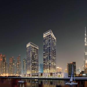 dois arranha-céus altos numa cidade à noite em DAMAC MAISON PRIVE em Dubai
