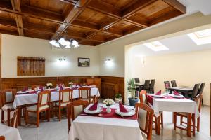 a restaurant with white tables and chairs and wooden ceilings at Juliu's Panzio Csikszereda in Miercurea-Ciuc