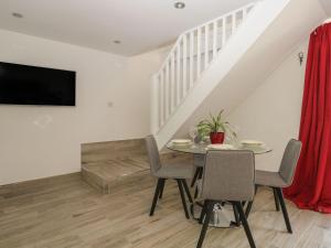 a dining room with a table and chairs and a tv at Broadford Barn - Barn conversion in picturesque village in Shalford