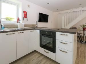 uma cozinha com armários brancos e um forno preto em Broadford Barn - Barn conversion in picturesque village em Shalford