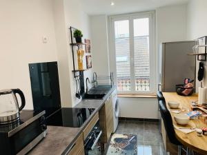 a kitchen with a counter and a table and a window at Nice cocooning apartment for a relaxing moment in Reims