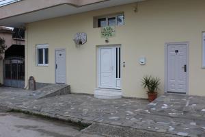 a white building with two doors and a potted plant at HAROULENA in Kavála