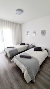 two beds in a bedroom with white walls and wood floors at Consolação Beach Apartment in Peniche