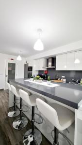 a kitchen with white cabinets and a bar with stools at Consolação Beach Apartment in Peniche