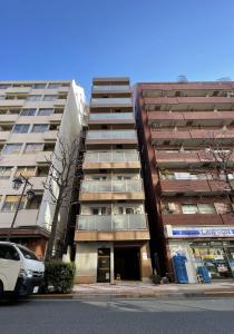 dos edificios altos en una calle con un coche aparcado delante en Dash Living Shinjuku, en Tokio