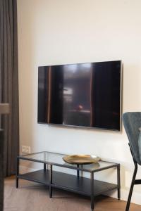 een woonkamer met een glazen salontafel en een flatscreen-tv bij Strand, Zee & Meer in Vrouwenpolder