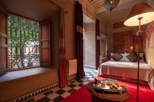 een slaapkamer met een bed, een raam en een tafel bij Riad Bohémia in Marrakesh