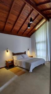 a bedroom with a large bed and a large window at Paiol Eco Suites in Paraty