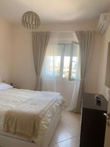 ein Schlafzimmer mit einem weißen Bett und einem Fenster in der Unterkunft Apartament Orestiada in Vlorë
